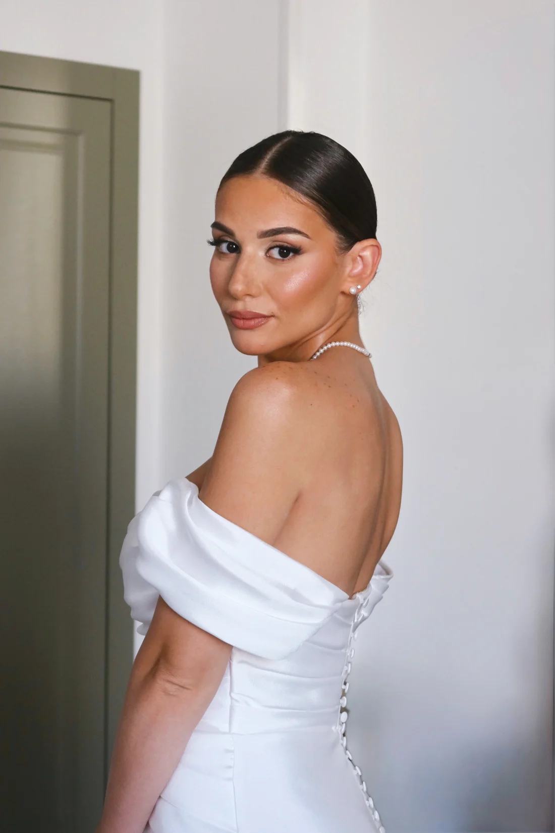 Sposa in raso bianco, con raccolto e makeup luminoso